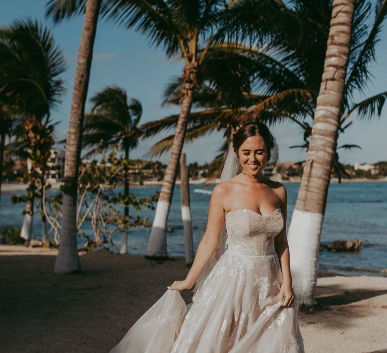 Bride smiles and looks down on her wedding day as she holds her wedding gown