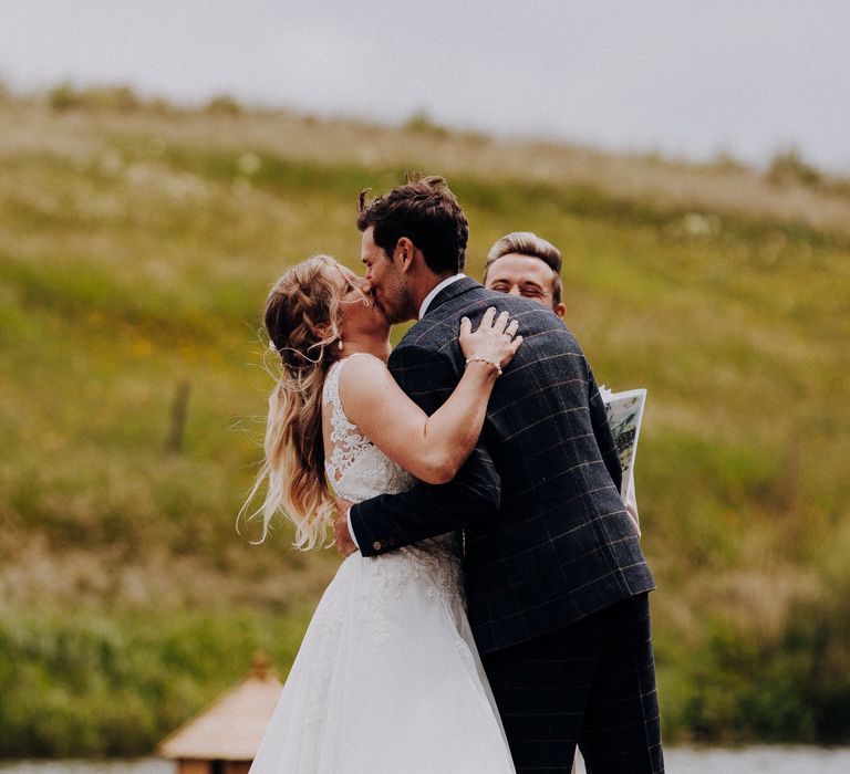 Groom leans bride back to kiss her during wedding ceremony