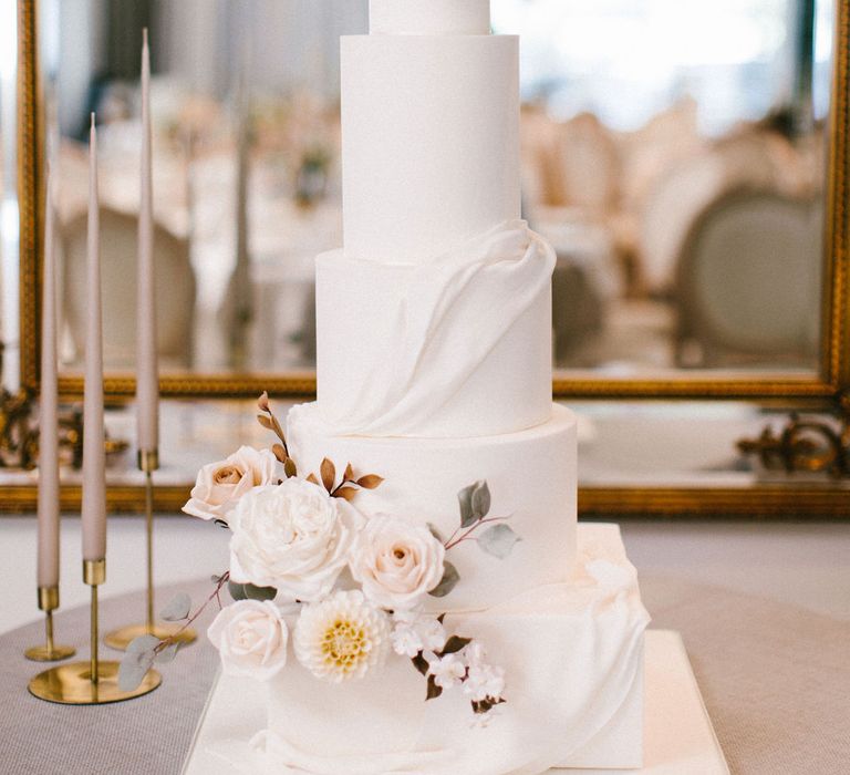 Elegant iced wedding cake with square and round layers and floral decor 