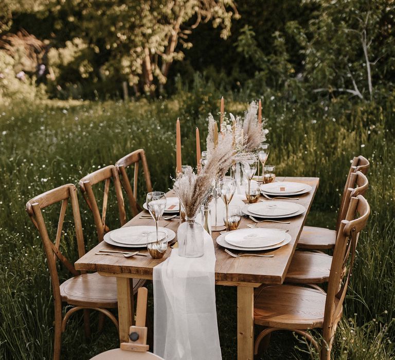 Meadow wedding with outdoor reception with wooden table and round wedding welcome sign 