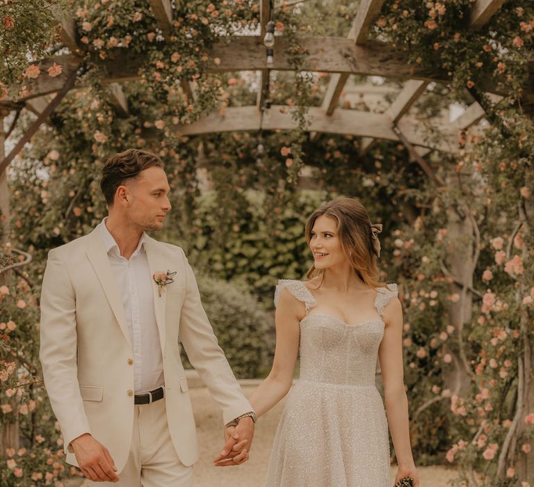 Bride and groom portrait under the pergola at Euridge Manor with groom in a stone suit and brown loafers and bride a sparkly Made With Love wedding dress