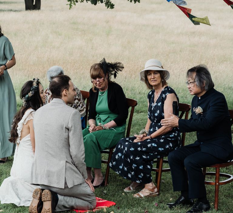 Bride & groom kneel during tradition Chinese Tea Ceremony outdoors