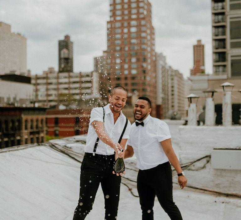 A gay couple open champagne on a New York rooftop. 