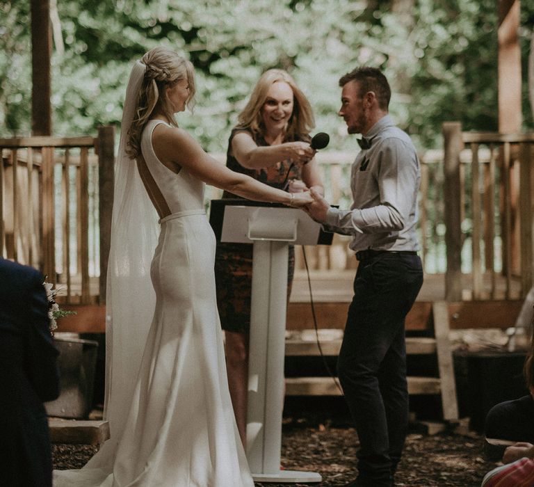 Groom speaks into microphone on his wedding day as he holds his brides hands