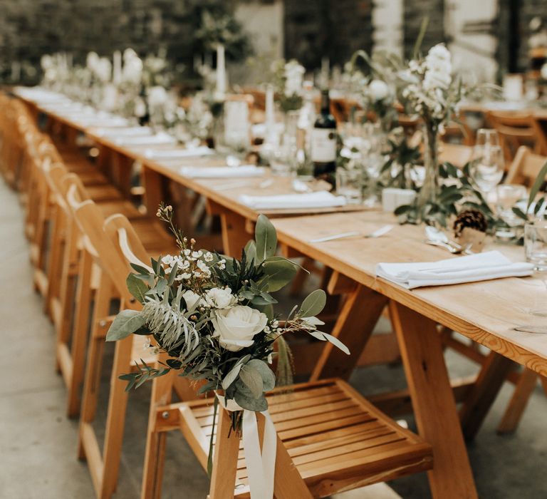 Foliage and white flower chair decor at rustic wedding