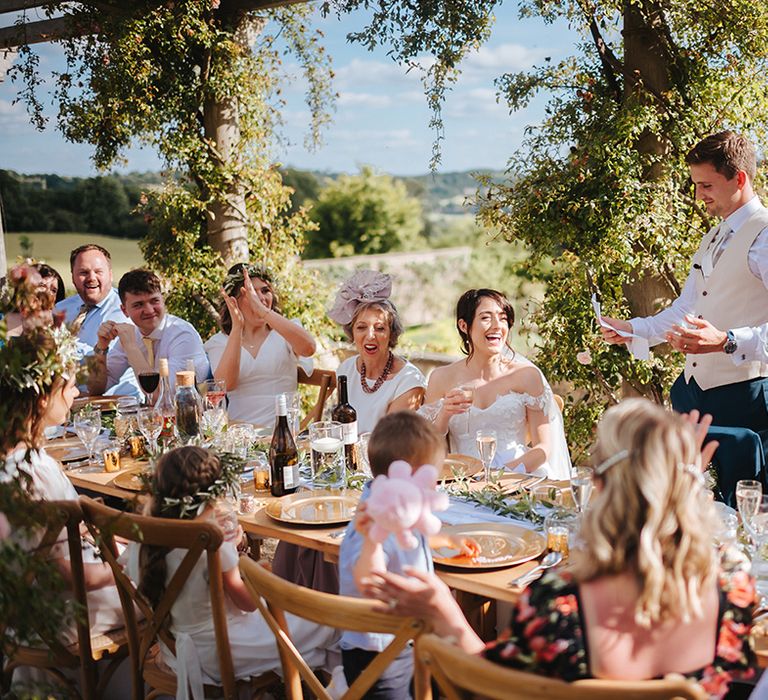 Groom reads wedding speech as guests clap and smile 