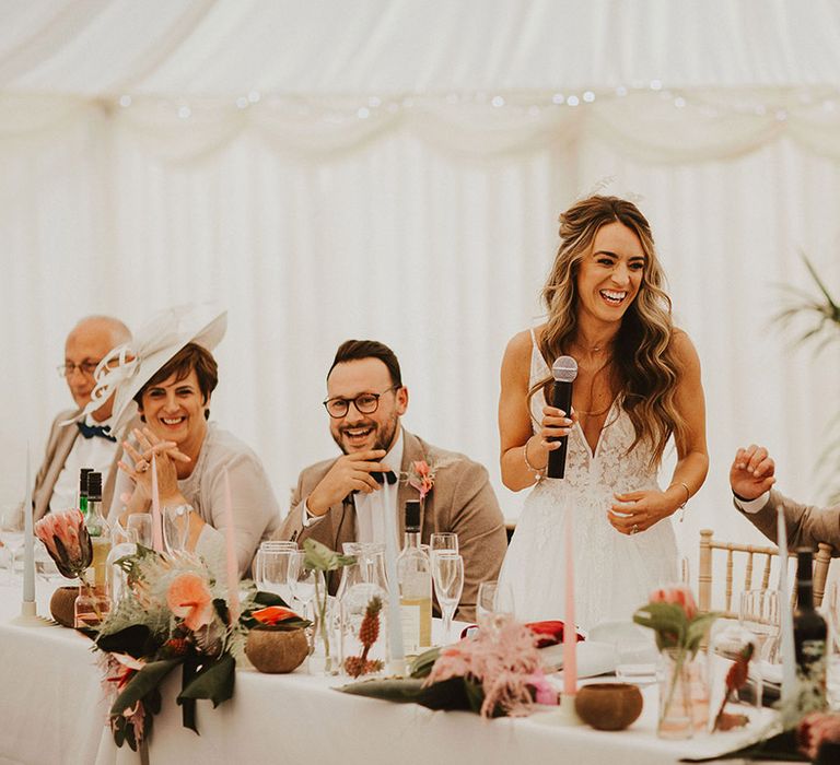 Bride gives speech on her wedding day as she holds microphone 