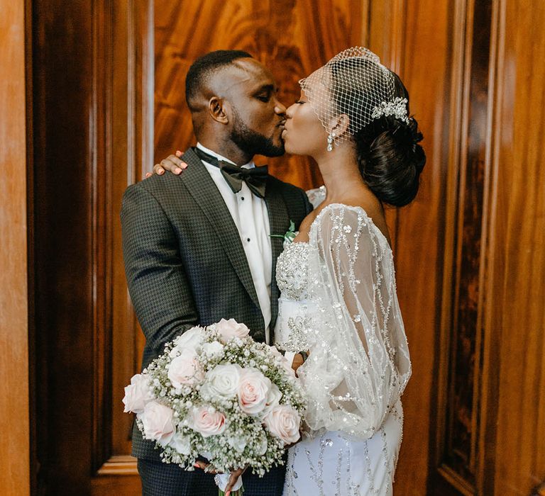 Bride & groom kiss on their wedding day as bride wears birdcage veil complete with statement earrings