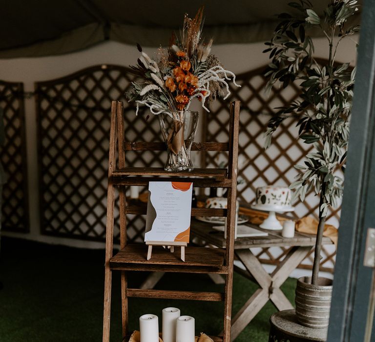 vintage step laser decorated with candles and dried orange wedding flowers 