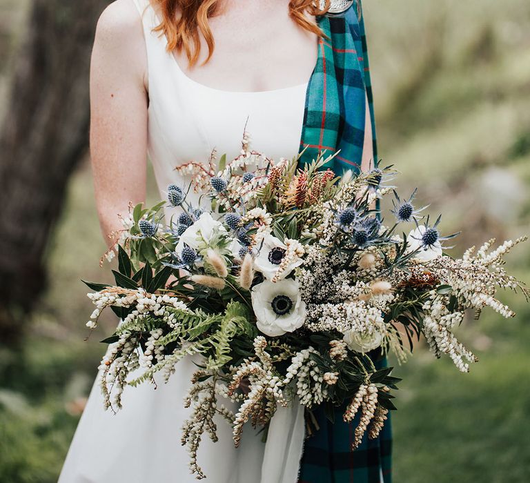 beautiful bride with red hair with hair up half down braided hairstyle holding an anemone, thistle and wildflower wedding bouquet 