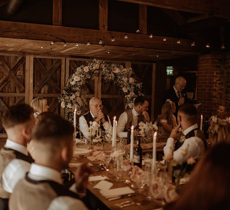 Dewsall Court wedding reception with pink flower and gypsophila flower arch behind the top table and taper candles table decor 