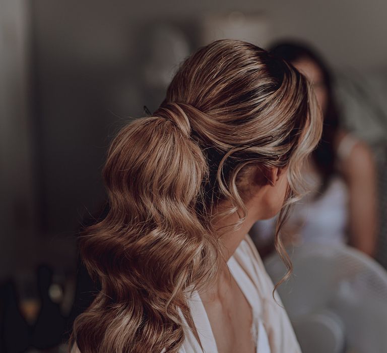 Bride wears her hair in ponytail with waves on her wedding day