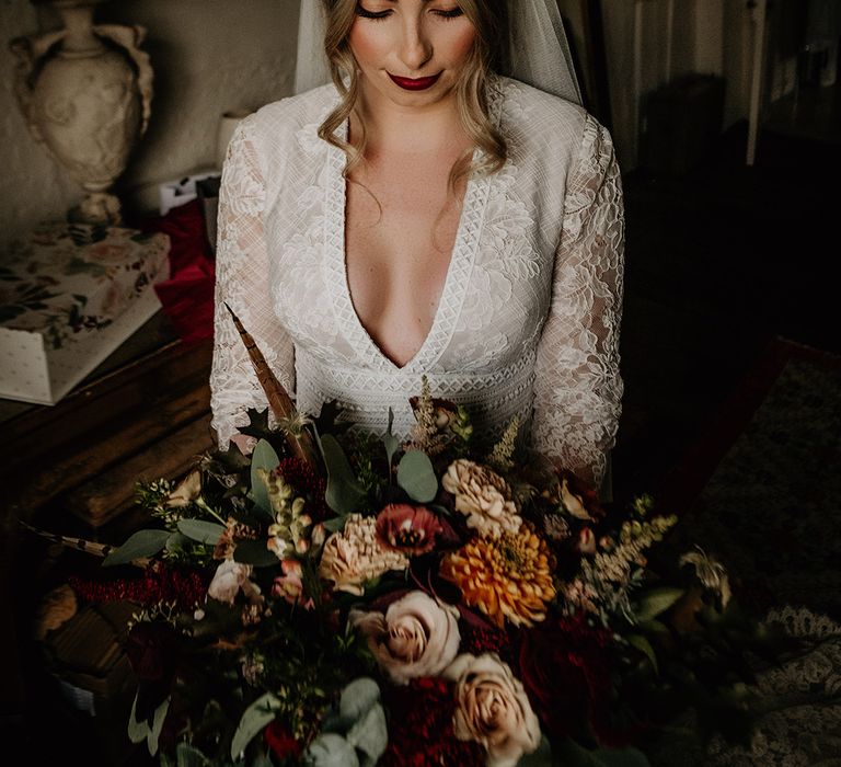 Beautiful bride with red lipstick in a lace wedding dress with plunging neckline and Juliet cap veil 