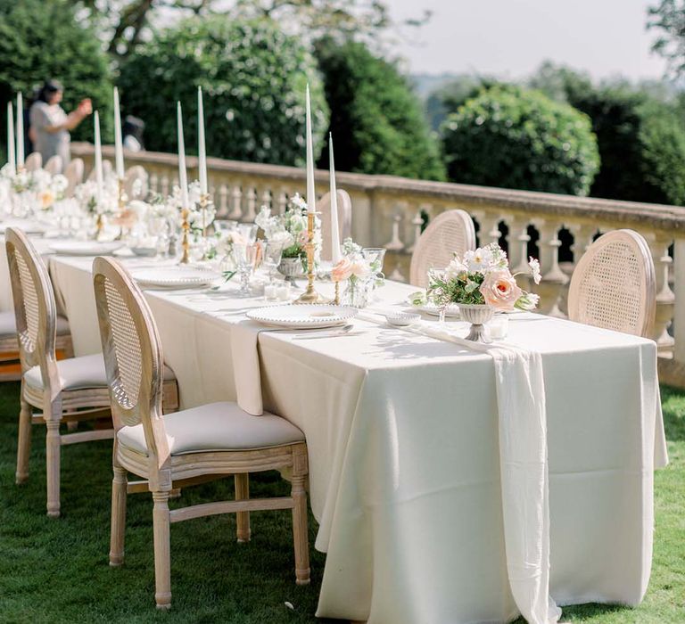 Long table complete with white table cloth and pastel florals lining the middle 