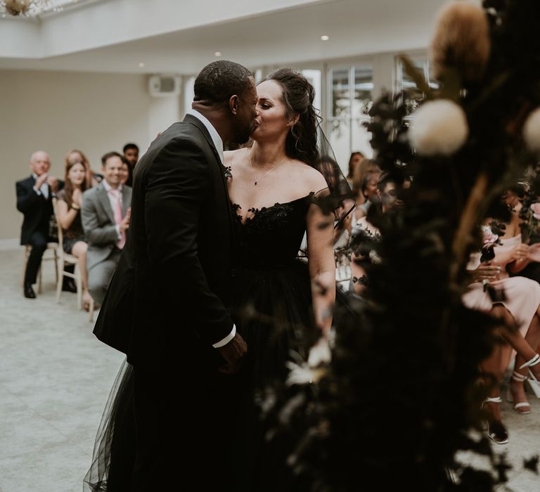 Bride & groom kiss on their wedding day as bride wears black wedding gown