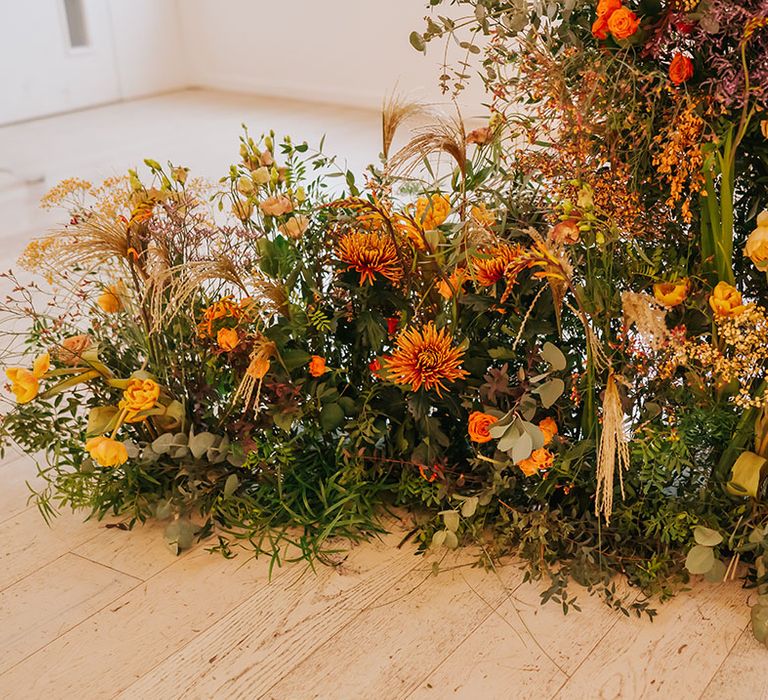 ceremony wedding flower arrangement with foliage, orange and yellow flowers