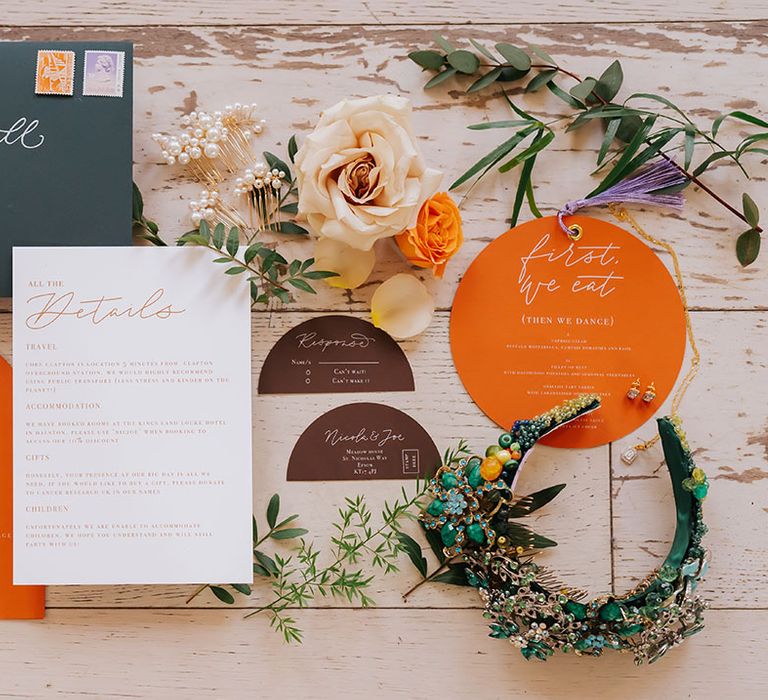 flatlay of an orange wedding stationery suite with bridal hair accessory