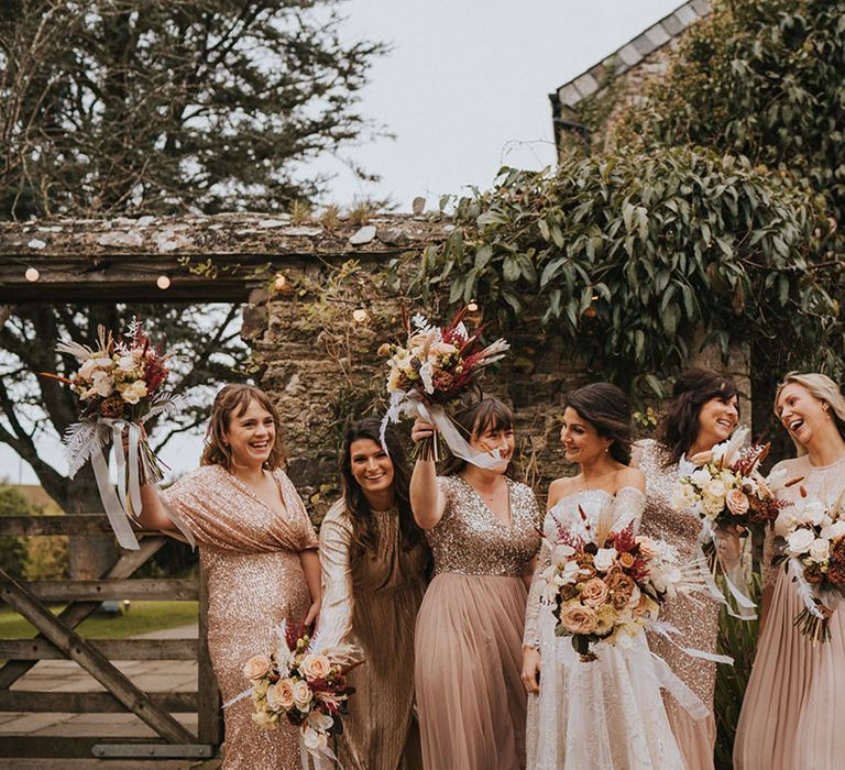 Bride in Zavana Couture wedding dress poses with bridesmaids in pink sparkly dresses with light and dark bouquets