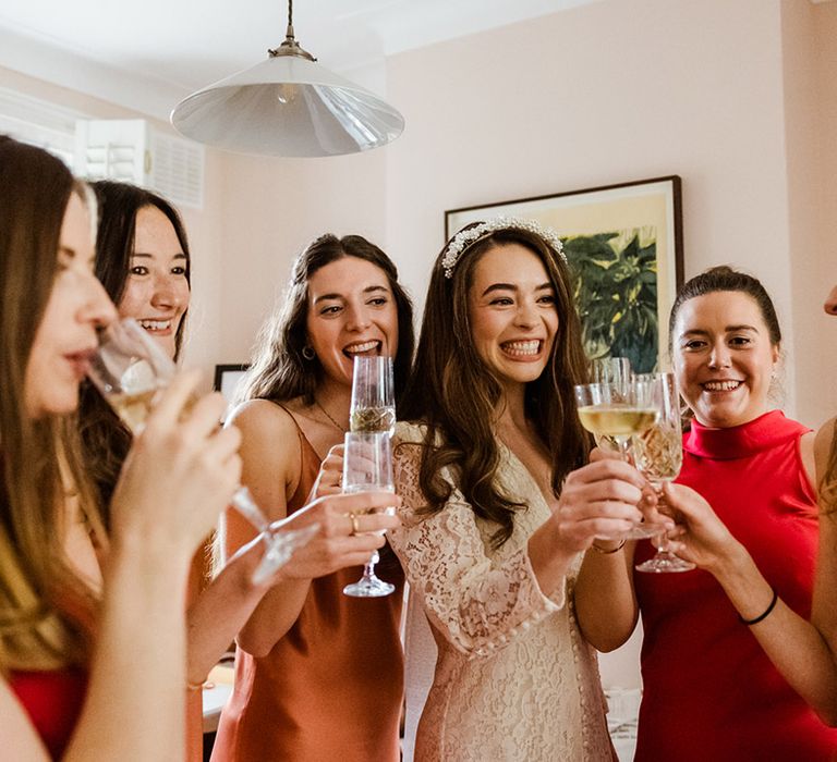 Bride wearing pearl cluster headband has a cheers with her bridesmaids in autumnal toned dresses