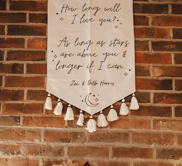 Bespoke white wedding banner with song lyrics and the couple's names for wedding decor