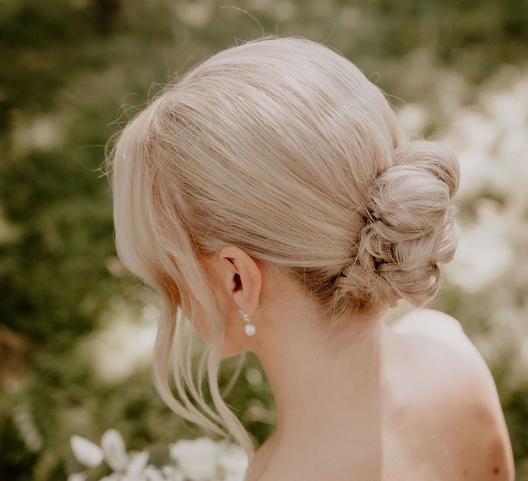 Bride with white blonde hair in an updo with pearl earrings for classic and traditional style wedding 