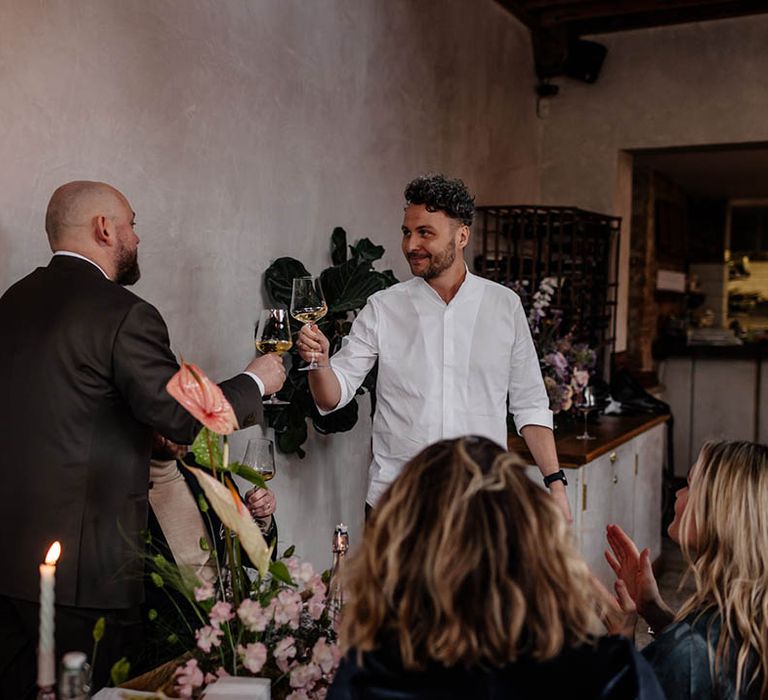 Groom and best man toasting at wedding reception 