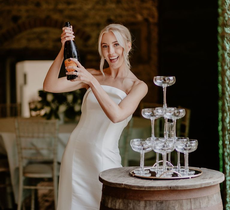 Bride in strapless gown pops Prosecco for their champagne tower 