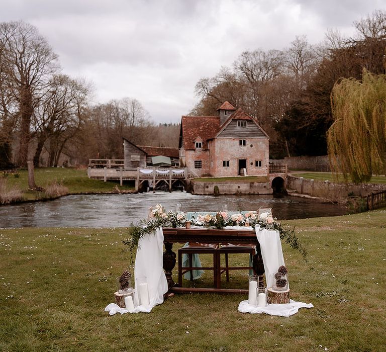 Outdoor wedding reception table at Mapledurham with white drapes and a foliage and pink flower table runner 