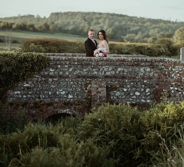 Bride and groom stand and pose together in the grounds around the wedding venue 