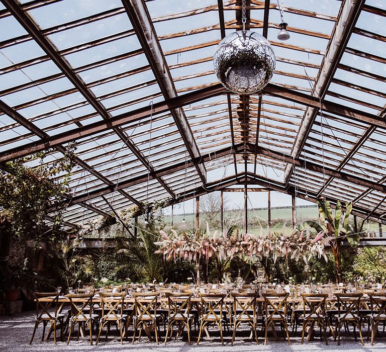 Glasshouse wedding venue with disco ball and large pampas grass flower cloud installation 