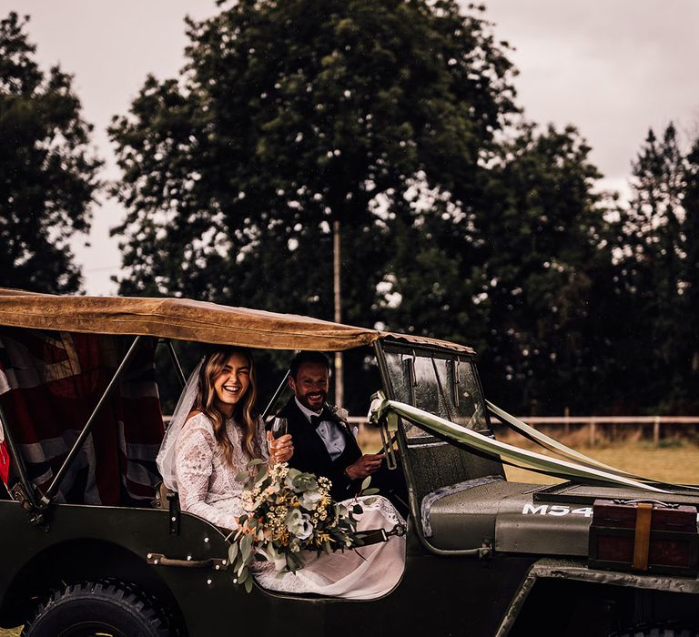 Bride and groom sit in their Jeep wedding car decorated with a Great Britain flag and green and white ribbon 