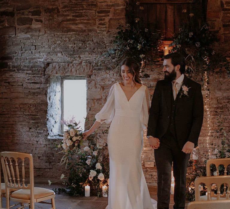 Pillar candles and foliage line the aisles as the bride and groom walk back down the aisle 