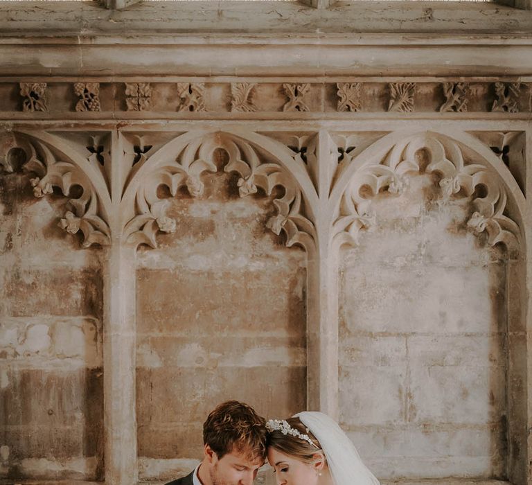 Bride and groom rest their foreheads against each other for their cathedral wedding 