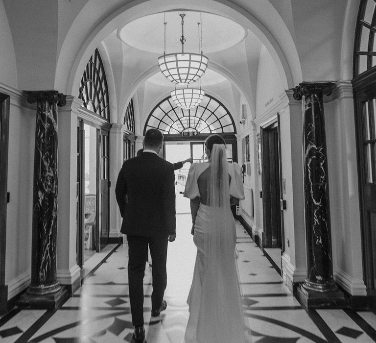 Bride with polka dot lace veil and open back detail wedding dress walking with groom in dark tux through Somerset House venue