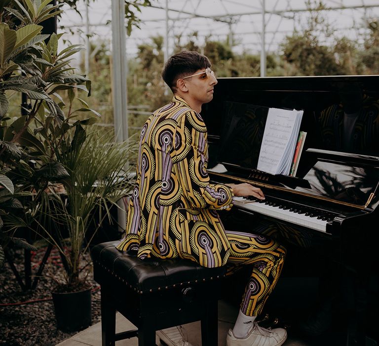 Bride's brother plays piano during ceremony whilst wearing a colourful patterned suit