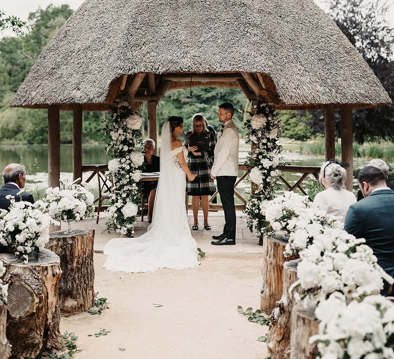 Classic and elegant white flowers line the aisle and decorate the altar in flower columns for the bride and groom's timeless traditional wedding 