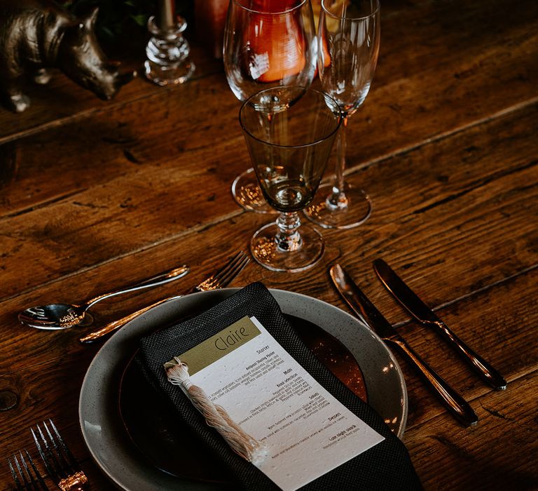 Speckled grey plates with black napkins and white and green wedding menu and place names 