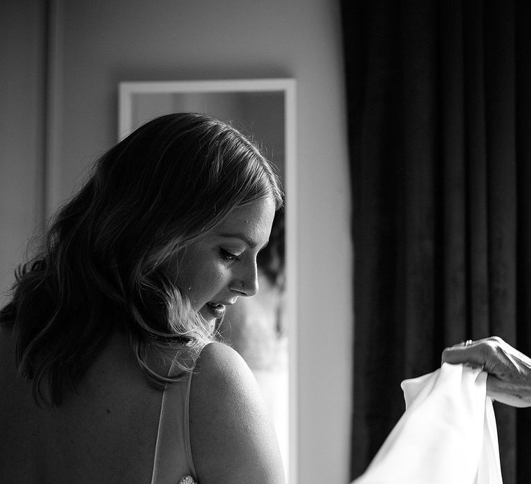 Bride gets into her wedding dress as she gets ready for the day 