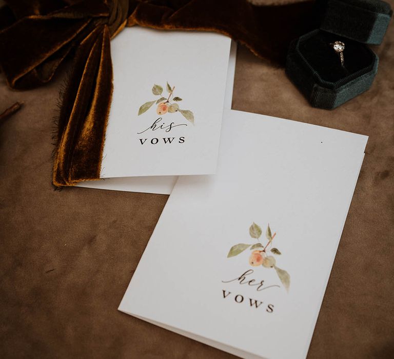 Minimalistic luxe wedding vows with watercolour paintings and large rust coloured velvet bow next to velvet green wedding ring holder