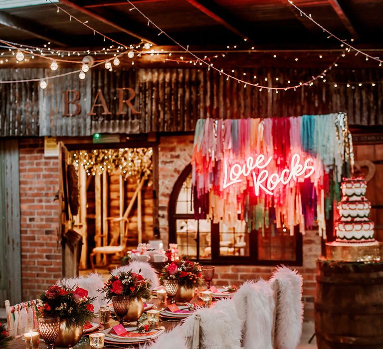 Contemporary, rustic wedding tablescape with hot pink plates, hot pink place names, gold candleholders, gold vase centrepieces with rose, peony and dried flower floral arrangements and faux fur throws 