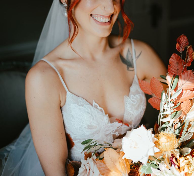 Bride wears lace Madi Lane Bridal wedding dress and holds burnt orange bridal bouquet 