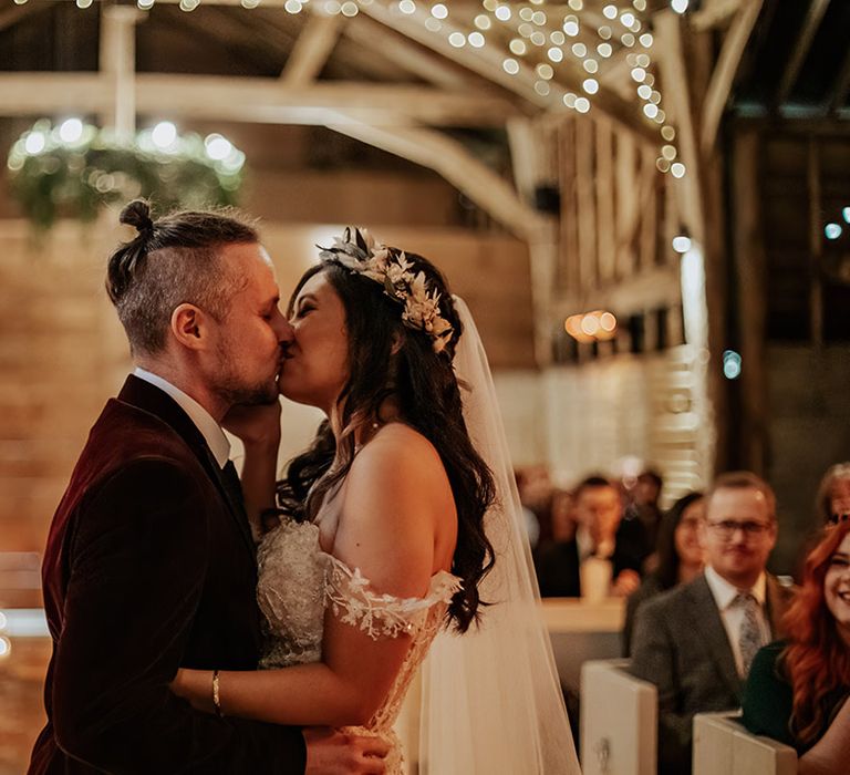 The bride and groom share their first kiss as a married couple for a boho autumnal barn wedding 