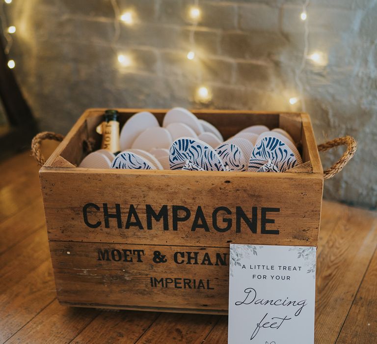 Rustic wooden box full of flip flops with a sign fro guests to help themselves to the flip flop wedding favours 