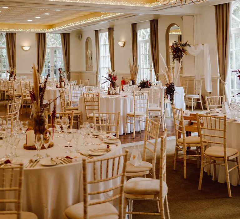 Reception room at The Orangery Maidstone with classic wedding tablescapes - white tablecloths, pampas grass centrepieces, pillar candles and wooden slates 