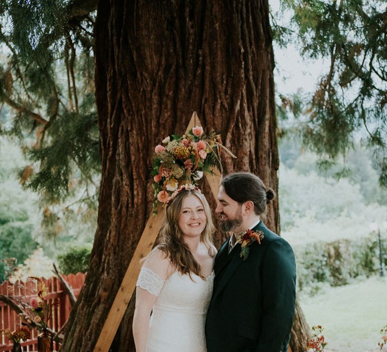 Outdoor wedding ceremony with triangle frame altar and off the shoulder lace wedding dress