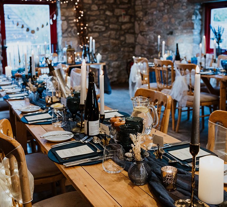 Navy blue table runner and plates with chairs decorated with sheer white bow and fairy lights for night sky theme wedding 