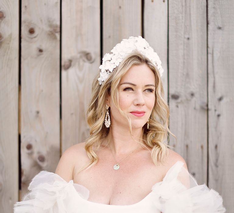 Bride wearing a ruffle layered Halfpenny London gown with white crown and dangly earrings 