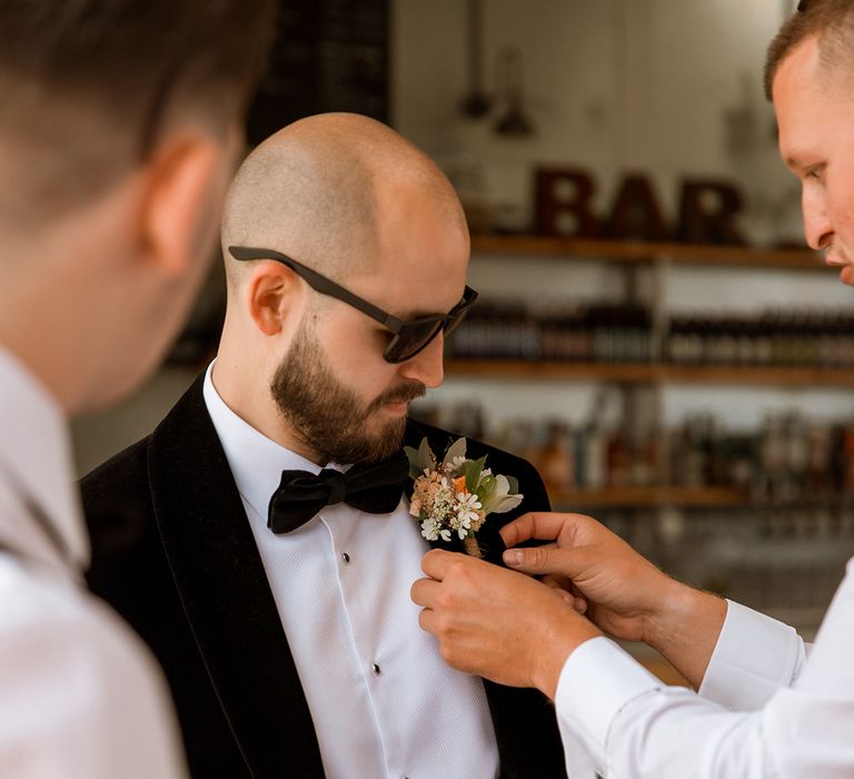 Groom wearing black wedding sunglasses with wedding buttonhole 