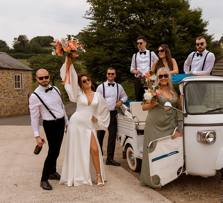 The wedding party pose around unique tuk tuk wedding transport 