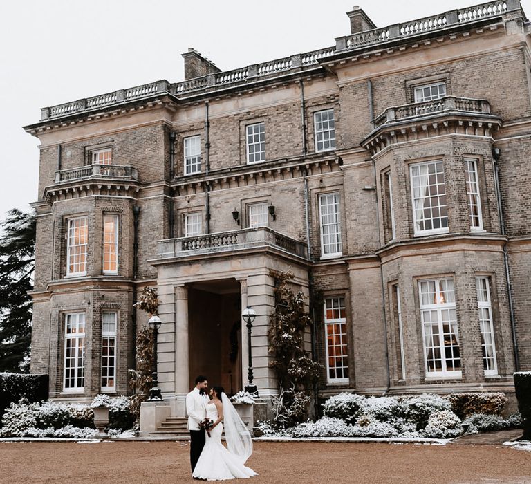 Hedsor House country house wedding venue with bride and groom standing in front of the venue 